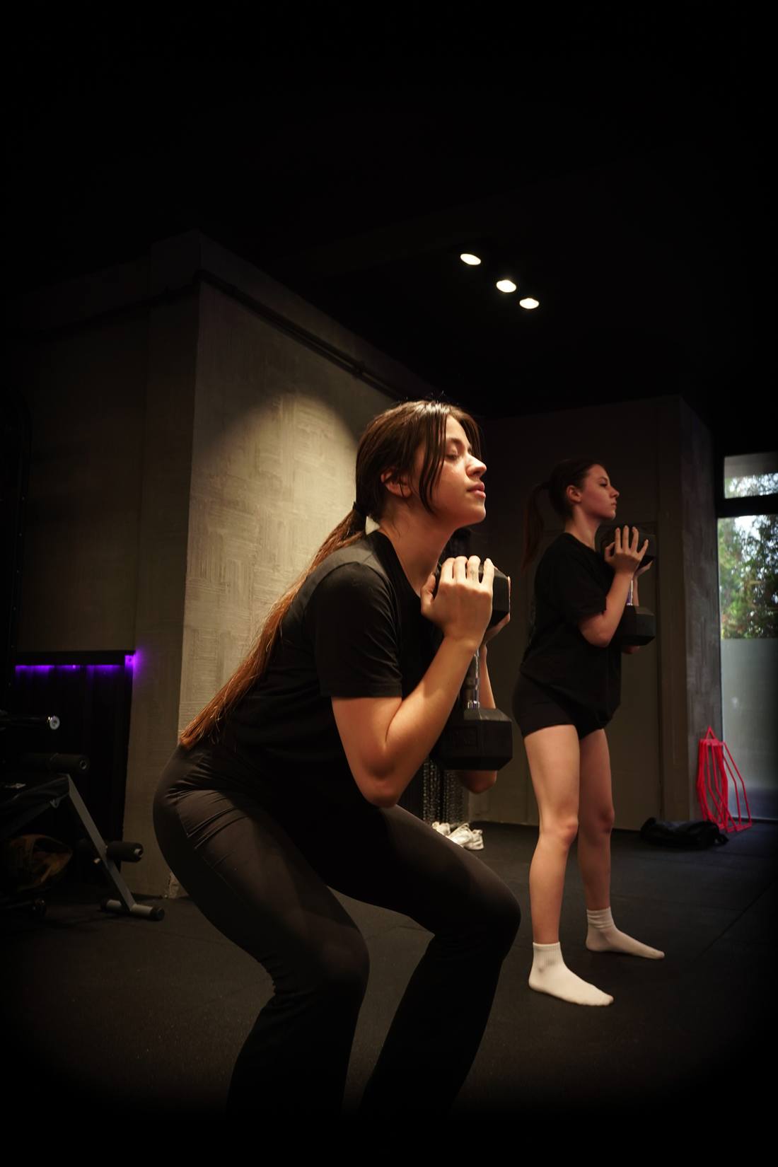 ACK Fitness stüdyosunda aynanın önünde dambılla lunge egzersizi yapan kadın